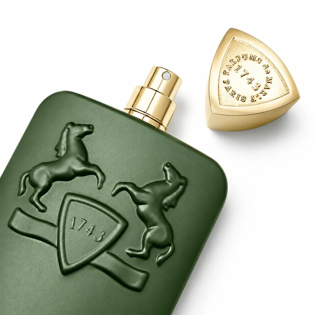 A dark green rectangular perfume bottle with a gold spray nozzle, featuring embossed horse and shield crest details, shown alongside its matching gold cap on a white background.