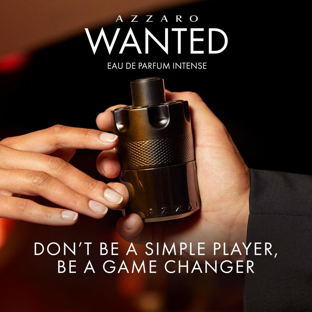 Azzaro Wanted perfume bottle held by a hand with promotional text on a dark background