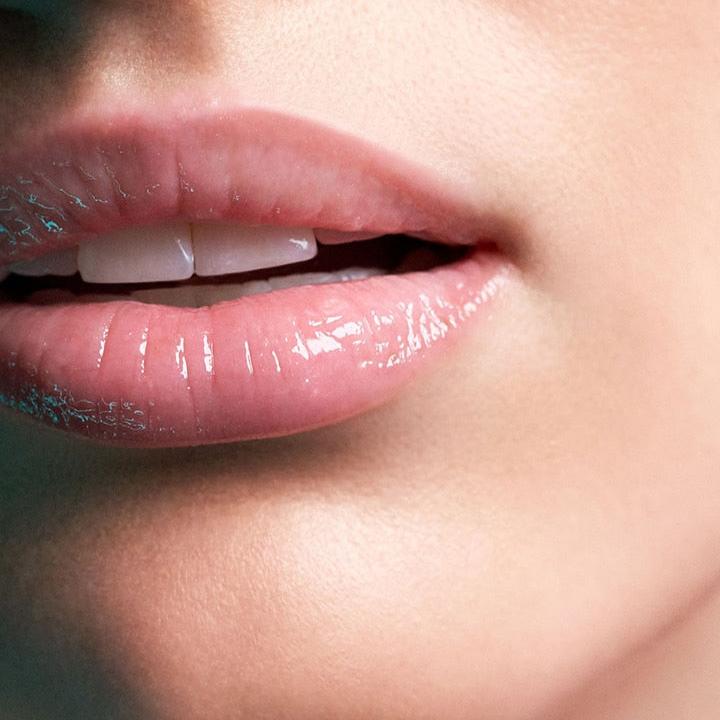 Close-up of a female showing her lips after applying La Mer The Lip Volumizer. The result is visibly plumper and more hydrated lips with a natural shine.